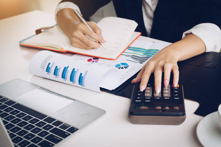 Business woman working with financial data hand using calculator and writing make note with calculate.Business financial and accounting concept.